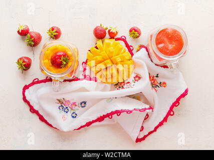 Gläser mit Erdbeeren und Mango Smoothies auf weißem Hintergrund, Ansicht von oben. Gesunde Früchte und Beeren Frühstück Stockfoto