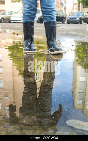 3 Jahre jungen Spaß an der städtischen Pfütze. Grundriss Stockfoto