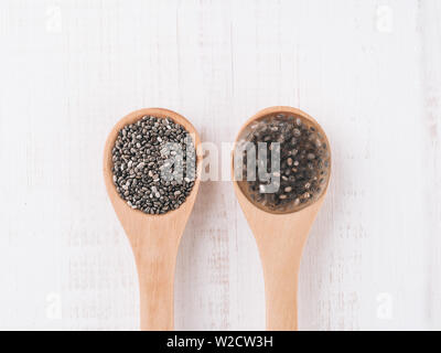 Trocken und Nass Chia Chia Samen Samen oder Chia-Ei in Holzlöffel auf weißem Holz- Hintergrund. Eiersatzprodukte, Eiern, veganer Eier Konzept ersetzen Stockfoto