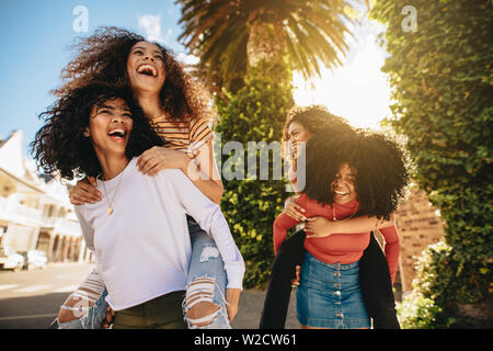 Junge Frauen genießen, sich im Freien begeistert. Gruppe von weiblichen Freunde huckepack und viel Zeit in der Stadt. Stockfoto