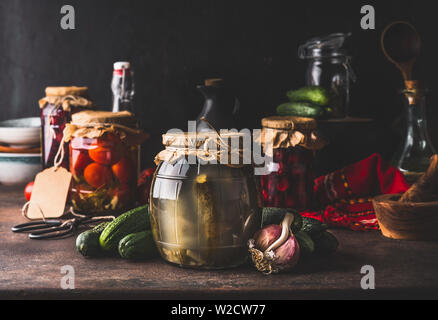 Konzept der Ernte zu erhalten. Gläser mit Fermentiert, eingelegtes und eingemachtes Gemüse und Früchte auf dunklen rustikalen Küche Tisch. Erhaltung der Farm Orgel Stockfoto