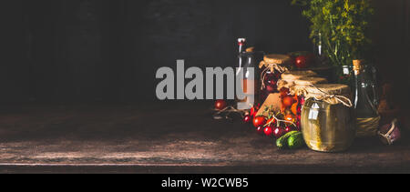 Essen Hintergrund mit einer Vielzahl von erhaltenen fermentiertes Gemüse und Obst aus dem Garten in Gläsern auf dunklen rustikalen Hintergrund. Herbst canning. Conserv Stockfoto