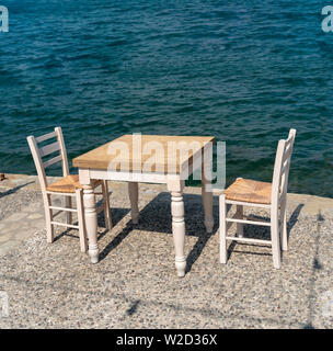 Ierapetra, Kreta, Griechenland. Juni 2019. Tisch und zwei Stühle stellen Sie dem Kunden die Verwendung am Kai in diesem südlichen Kreta Resort. Stockfoto