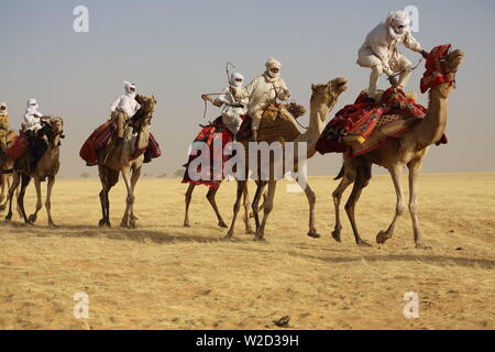 Beduine reitet auf Kamel durch sandige Wüste. Stockfoto