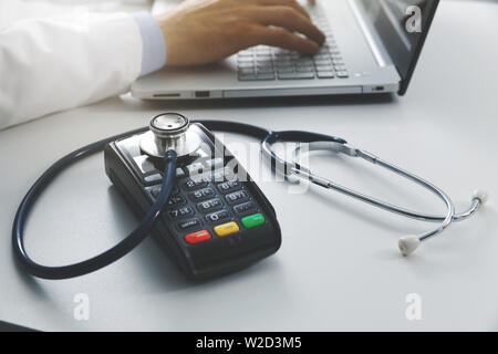 Medizinische Kosten und Gesundheitsausgaben Konzept - Payment Terminal mit Stethoskop auf die Tabelle in den Doktorbüro Stockfoto