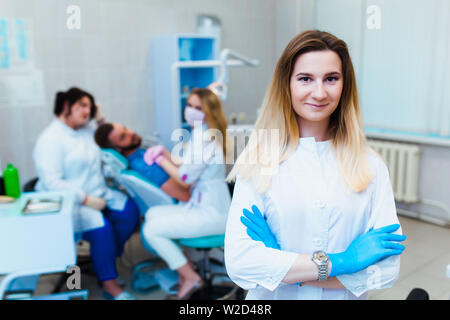 Zahnmedizinische Klinik. Porträt eines professionellen Zahnarzt auf dem Hintergrund einer Arbeitsgruppe der Ärzte. Konzept der medizinischen Ausbildung und der Krankenversicherung. Stockfoto