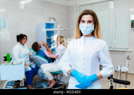 Zahnmedizinische Klinik. Porträt eines professionellen Zahnarzt auf dem Hintergrund einer Arbeitsgruppe der Ärzte. Konzept der medizinischen Ausbildung und der Krankenversicherung. Stockfoto