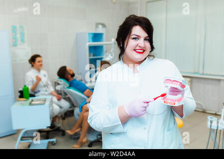 Zahnmedizinische Klinik. Porträt eines professionellen Zahnarzt auf dem Hintergrund einer Arbeitsgruppe der Ärzte. Konzept der medizinischen Ausbildung und der Krankenversicherung. Stockfoto