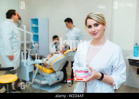 Zahnmedizinische Klinik. Porträt eines professionellen Zahnarzt auf dem Hintergrund einer Arbeitsgruppe der Ärzte. Konzept der medizinischen Ausbildung und der Krankenversicherung. Stockfoto