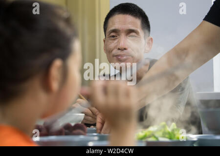 (190708) - LINHAI, Juli 8, 2019 (Xinhua) - Wu Yuanmiao und seine Familie haben Abendessen in Lucheng Gemeinschaft von Linhai, Stadt, der ostchinesischen Provinz Zhejiang, 26. Juni 2019. Wu Yuanmiao, beim Arbeiten als ein Friseur, ein Regelsatz für sich kostenloser Service ein Tag in der Woche an die Alte, Behinderte, und Soldaten. Mit mehr als 60.000 Kunden für 17 Jahr diente, ist er der Gewinner zahlreicher Auszeichnungen, darunter 1. Mai Arbeit Medaille. Aber bestimmt mit Erkrankungen des Gehirns, Wu's Zustand schlechter seit 2008 wurde. Im Jahr 2014 erlebte er eine harte Zeit in seinem Friseur laufen und Pub Stockfoto