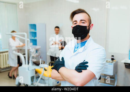 Zahnmedizinische Klinik. Porträt eines professionellen Zahnarzt auf dem Hintergrund einer Arbeitsgruppe der Ärzte. Konzept der medizinischen Ausbildung und der Krankenversicherung. Stockfoto