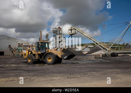 Abbau, Verwaltung und Transport von mineralischen Sanden aus Titan. Frontlader, der schweres mineralisches Sandkonzentrat vom Vorratstapel zum Trennwerk verschiebt. Stockfoto