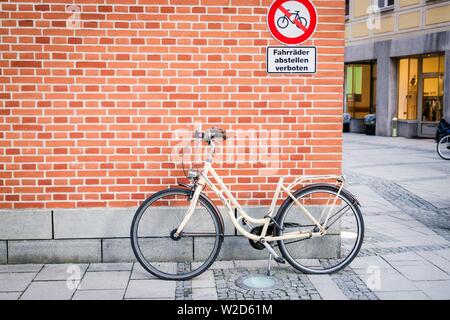 München, Deutschland. Februar 17, 2019. Fahrrad auf der Mauer Hintergrund. Inschrift in deutscher Sprache verbot Schild Parkplatz Fahrrad. Ungehorsam Konzept Stockfoto