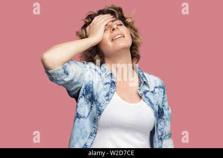 Portrait von traurigen sorgen junge Frau mit Curly Frisur im casual blaues Hemd stehen, die Hand auf die Stirn und traurig, weil alles verloren. indo Stockfoto