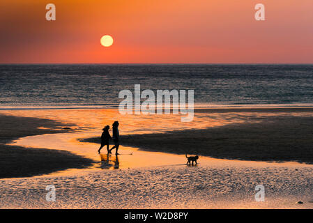 Menschen in Silhouette als einen wunderschönen Sonnenuntergang setzt auf den Fistral Beach in Newquay in Cornwall gesehen. Stockfoto