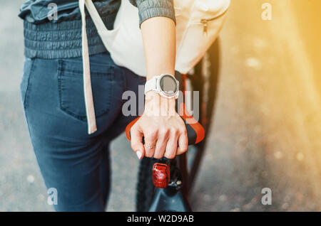 Die Mädchen Hand mit weißen Sport smart Watch auf dem Fahrrad Sattel. Stockfoto