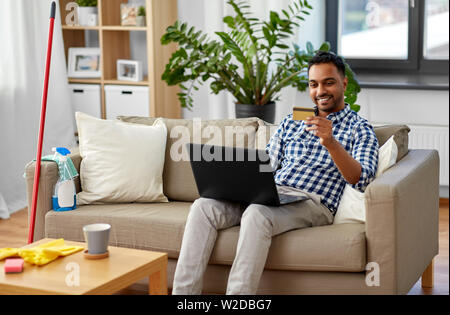 Mann mit Laptop online Einkaufen nach der Reinigung Stockfoto