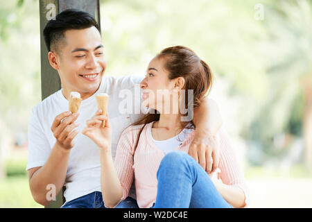 Schönen asiatischen Paar umarmen einander und Eis essen und reden miteinander im Freien Stockfoto