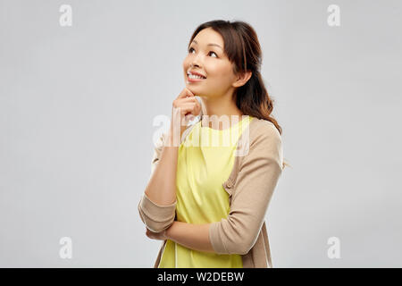 Gerne asiatische Frau über grauer Hintergrund Stockfoto