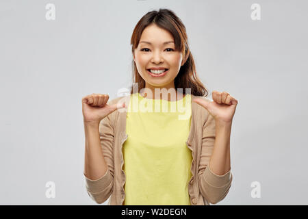 Gerne asiatische Frau zeigt Daumen zu sich selbst Stockfoto