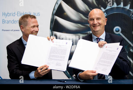 Cottbus, Deutschland. 08 Juli, 2019. Dietmar Woidke (SPD, r), Ministerpräsident des Landes Brandenburg, und Dirk Geisinger, CEO von Rolls-Royce Deutschland, präsentieren die unterzeichnet Absichtserklärung für die Entwicklung von Hybrid-elektrische Antriebe an der Brandenburgischen Technischen Universität (BTU) Cottbus-Senftenberg. Cottbus Universität und der Aircraft Engine Hersteller Rolls-Royce wollen ihre Zusammenarbeit bei der Entwicklung der teilweise elektrische Motoren weiter zu stärken. Credit: Monika Skolimowska/dpa-Zentralbild/dpa/Alamy leben Nachrichten Stockfoto