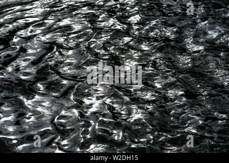 Die reflektierenden Sonnenstrahlen die Wogen und Wellen in einem Teich mit Springbrunnen. Stockfoto