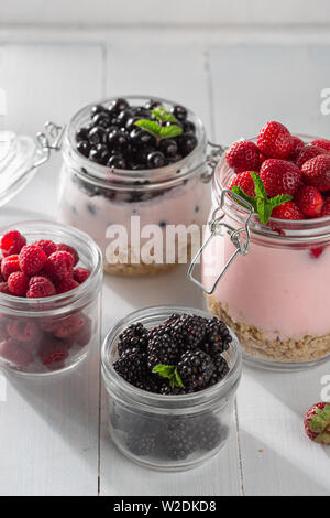 Gesundes essen Frühstück. Müsli Joghurt mit hausgemachten Erdbeere, Heidelbeere, Brombeere und Himbeere in Glas Glas in der Küche zu Hause Stockfoto
