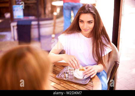 Aufnahme der jungen Frau im Café draußen sitzen und trinken ihr Espresso. Stockfoto