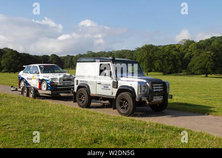 2003 Land Rover Defender 90 TD5 Schleppen 1989 80s weißer Ford Escort RS Cosworth bei der Classic Car Rallye. Mark Woodwards Oldtimer-Show im Hochsommer reiste zum malerischen Carnforth, um auf der diesjährigen Leighton Hall Transport Show weitere Klassiker, historische Motoren und Sammlerstücke zu präsentieren. Eine Gelegenheit, mehr als 500 Oldtimer vergangener Zeiten bei einer der umfangreichsten und vielfältigsten Shows des Sommer-Oldtimer-Events zu sehen. Stockfoto