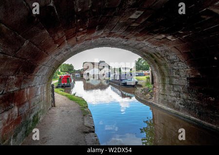 Blick entlang der Shropshire Union Canal in der Nähe von Market Drayton in Shropshire, Großbritannien, darunter auch Bridge 62 und Brücke 63 und der Talbot Wharf und Lastkähne Stockfoto