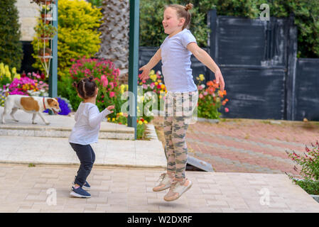 Zwei Entzückende kleine Mädchen, Springen, Tanzen, Lachen, Spaß im Freien. Happy Sommer Urlaub. Stockfoto
