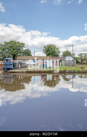 Blick entlang der Shropshire Union Canal in der Nähe von Market Drayton in Shropshire, Großbritannien, darunter auch Bridge 62 und Brücke 63 und der Talbot Wharf und Lastkähne Stockfoto