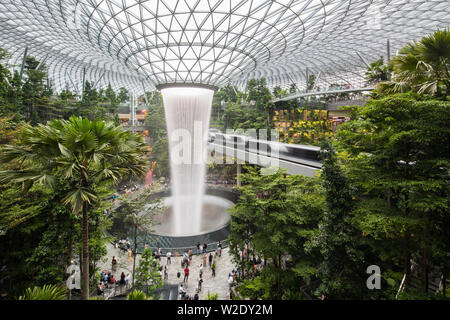 Landschaft Weitwinkelblick auf Jewel Changi Airport Hauptattraktion, riesiger Wasserfall. Zeitlupe des Skytrain und der Reisenden auf dem Boden. Singapur. Stockfoto