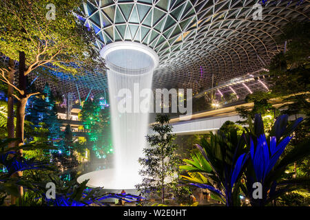 Nachtsichtbeleuchtung des Rain Vortex, größte und höchste Innenarchitektur für Wasserfälle, Jewel Changi Airport, Singapur. Stockfoto