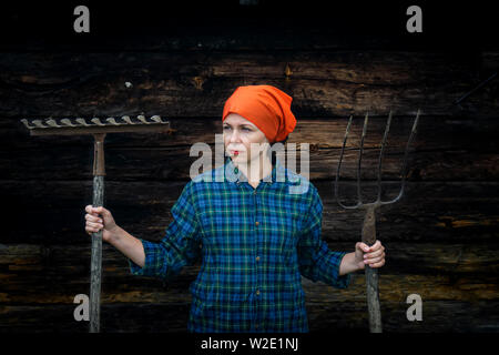 Junge Frau steht mit einer Heugabel in der Nähe von stable auf einer Ranch Stockfoto