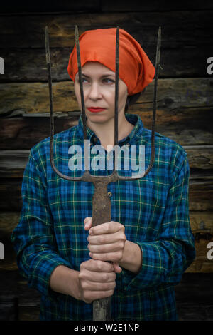 Junge Frau steht mit einer Heugabel in der Nähe von stable auf einer Ranch Stockfoto