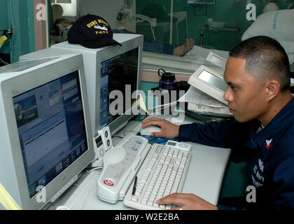 US Navy (USN) Hospital Corpsman zweiter Klasse medizinische Behandlung, US Military Sealift Command (MSC) Barmherzigkeit Klasse Hospital Ship USNS Mercy (T-AH 19), bereitet den Computer, bevor Sie eine computergestützte Axiale Tomogragphy (CAT) zu einem Patienten scannen, während eine humanitäre Mission zur Unterstützung. Stockfoto