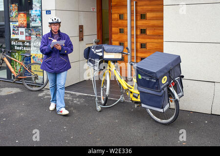 Französische postwoman und elektrische Lieferung bike Stockfoto