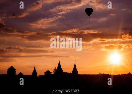 Blick auf die Burg in Kamianets Podilskyi und schwarz Heißluftballon während des Sonnenuntergangs. Die Ukraine Stockfoto