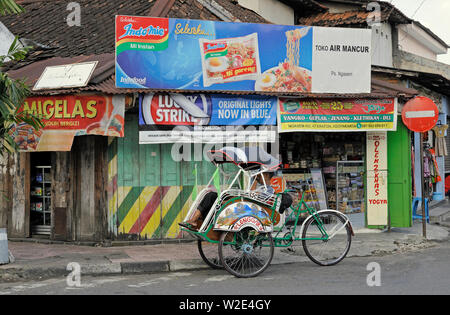 Yogyakarta, di in Yogyakarta/Indonesien - 27. April 2009: Ein becak Fahrer in seinem Fahrzeug warten auf Fahrgäste vor einem Geschäft Stockfoto