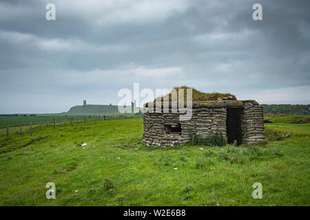 Weltkrieg zwei Pilllbox mit Dunstanburgh Castle in der Ferne, Northumberland, Großbritannien Stockfoto