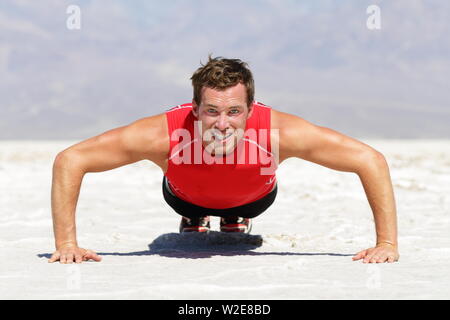 Fitness Mensch tun Push-ups Training Outdoor in wilden heißen Wüste Landschaft. Starke männliche Athlet tun Querschnitts Ausbildung Push up außerhalb zeigt Stärke und Entschlossenheit bestimmt. Stockfoto