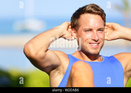 Fitness Mann tun, Sit-ups Outdoor. Close up Portrait von männlichen fitness Modell Ausbildung sitzen oben Übung während draußen trainieren Sie im Gras im Sommer. Schöne muskulöse Männer Sport Modell aus. Stockfoto