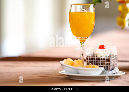 Orangensaft in Champagner Glas mit Kuchen und bagery Neben. Stockfoto