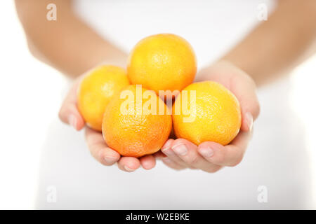 Clementine. Clementinen, die eine Vielzahl von Mandarinen Zitrusfrüchte. Frau, Handvoll. Im Studio mit einer geringen Tiefenschärfe auf weißem Hintergrund. Stockfoto