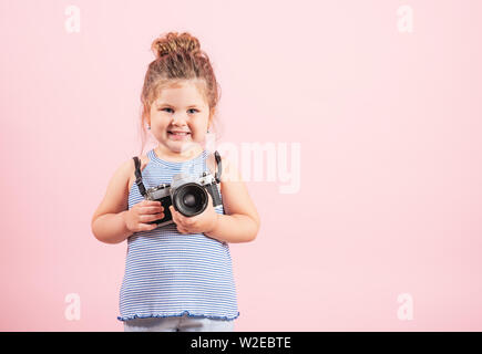 Kleines Mädchen mit alten Vintage Kamera und lächelnd auf rosa Hintergrund. Stockfoto