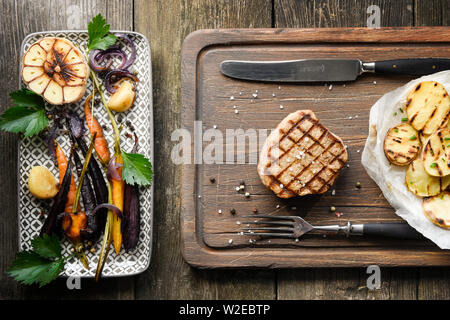 Steaks und gegrilltes Gemüse von oben auf Holz Tisch Stockfoto