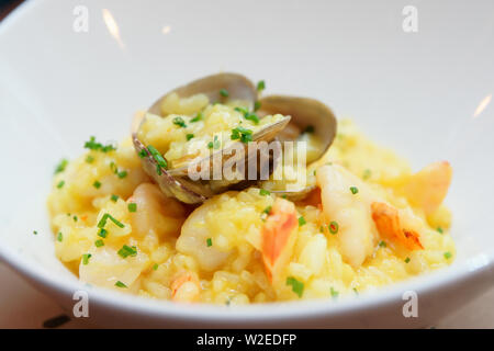 Safran Risotto mit Jakobsmuscheln und Garnelen in weiße Platte, close-up Stockfoto