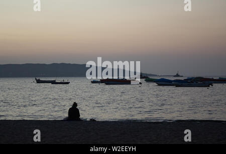 Frau am Strand sitzen bei Sonnenuntergang, Paracas, Peru Stockfoto