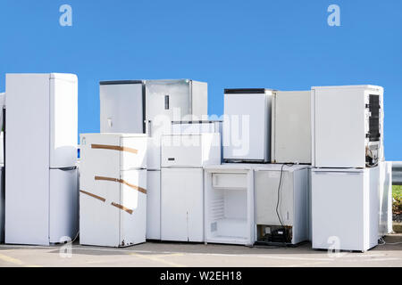 Alte Kühlschränke Gefriergeräte Gas als Kältemittel an der Müllkippe überspringen Recyceln gestapelt Stapel Hilfe Umwelt Reduzierung der Verschmutzung weiß Silber blauer Himmel Stockfoto